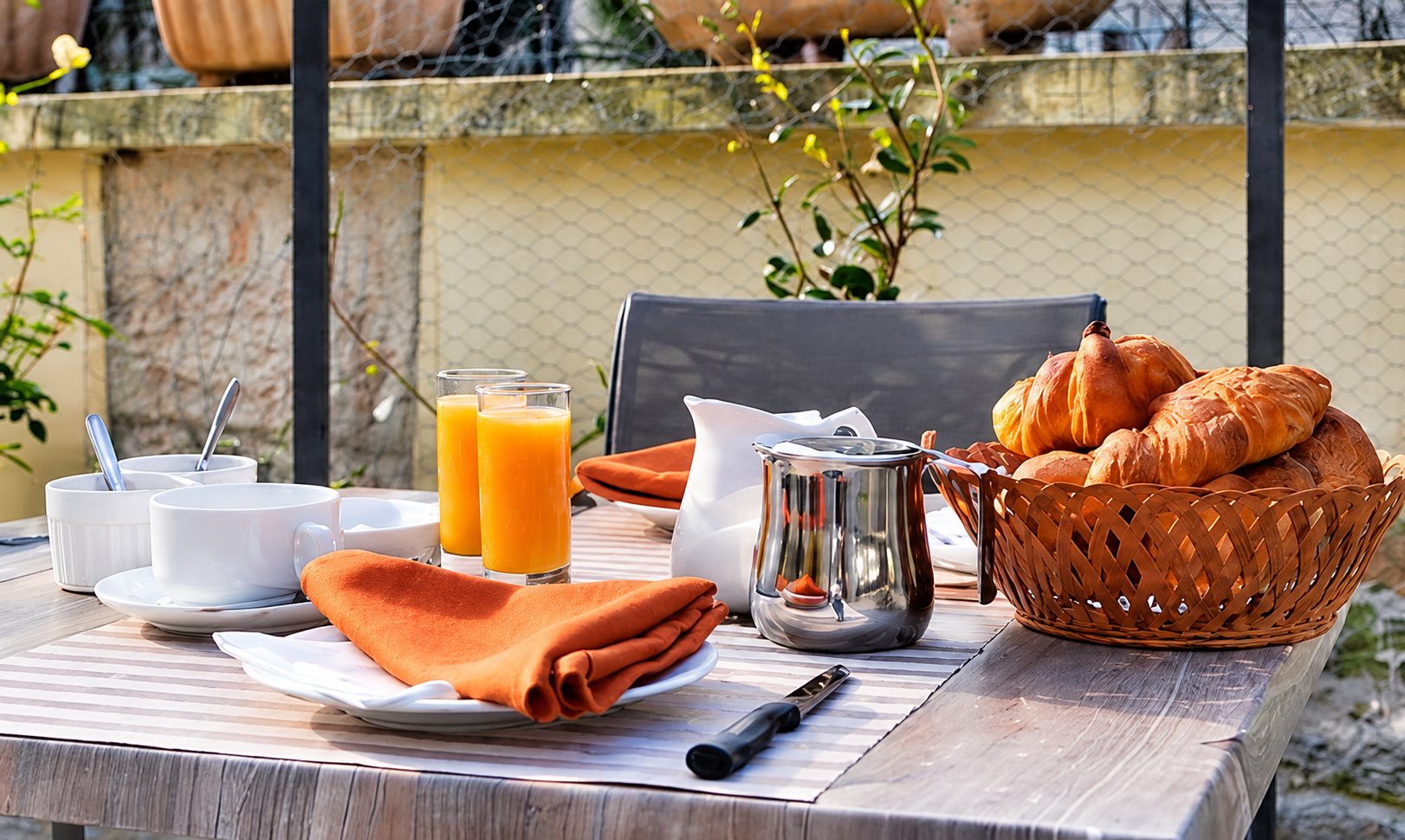 Table de petit-déjeuner sur la terrasse, avec croissants et jus d’orange